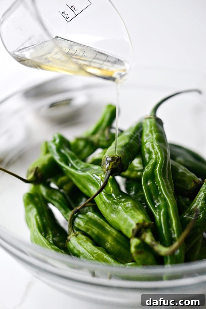 Drizzling shishito peppers with avocado oil in a bowl