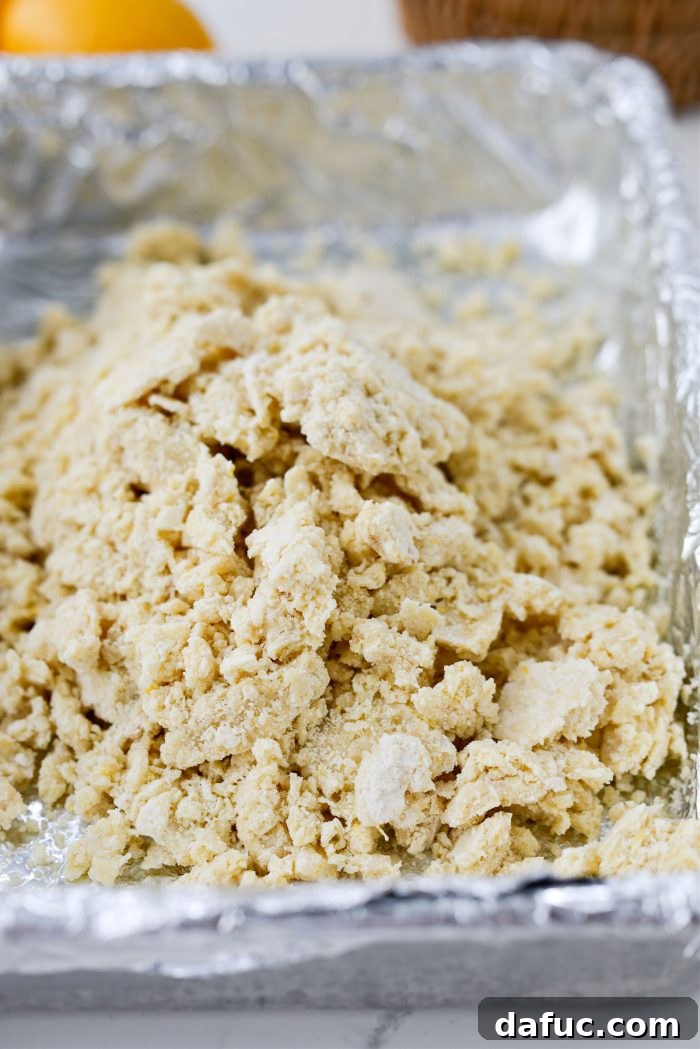 Shortbread dough being transferred to the prepared baking pan