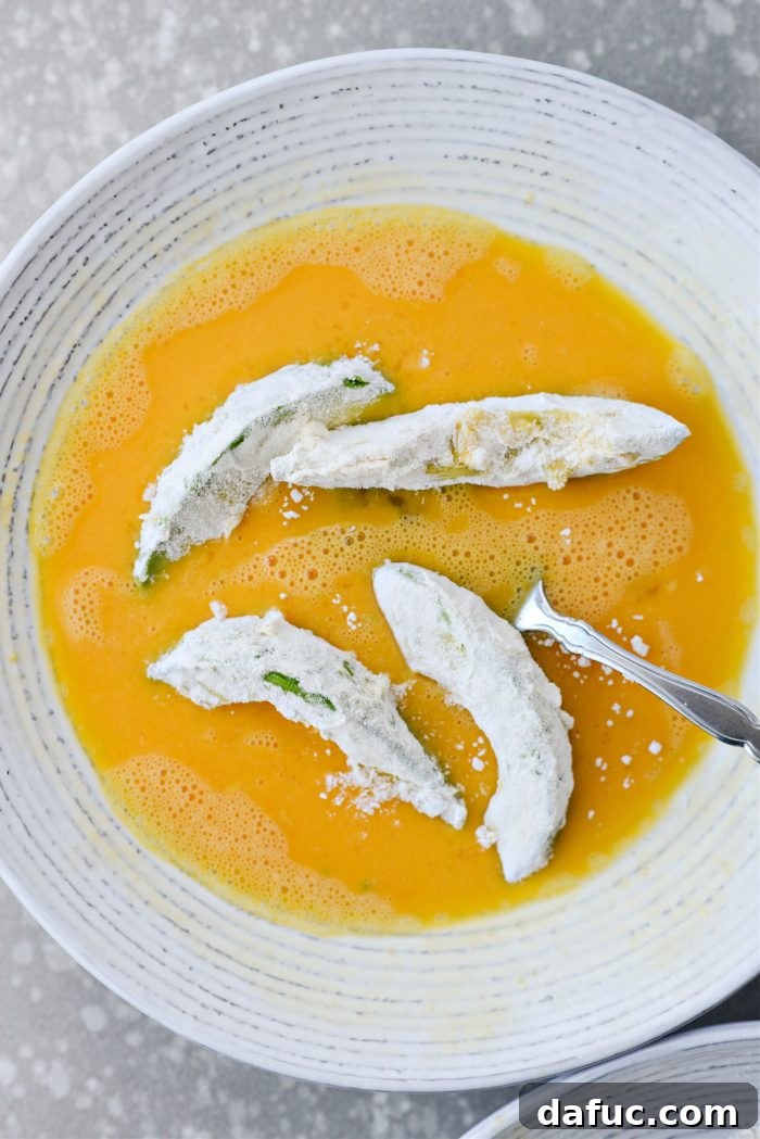 Dipping flour-coated avocado wedges in egg again