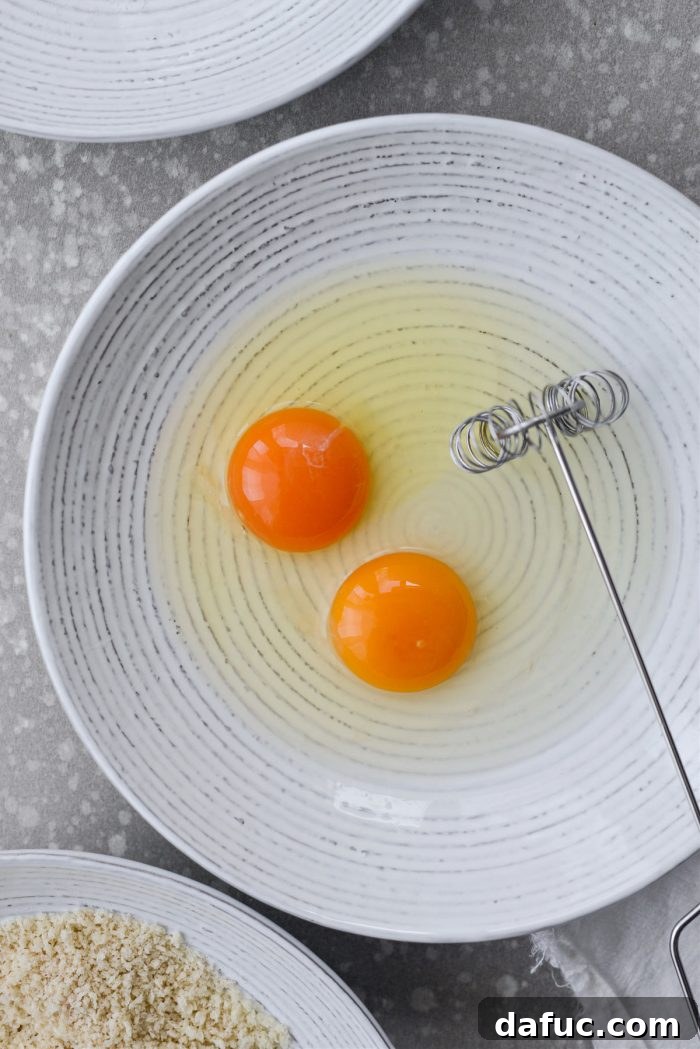 Cracking eggs into a bowl for the breading station