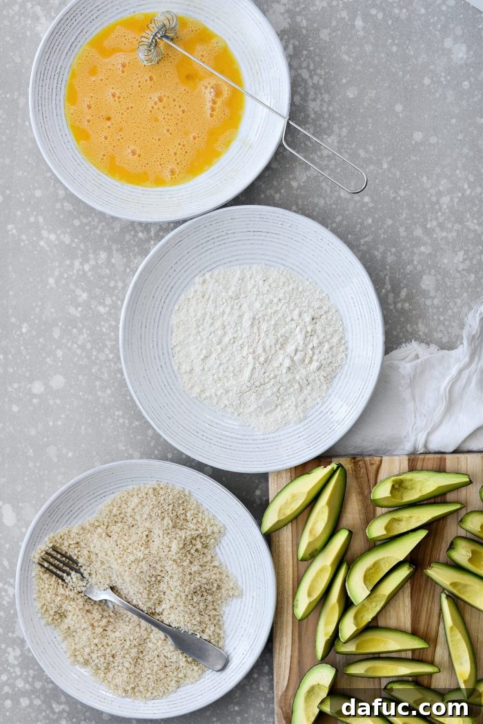 Organized breading station with bowls of egg, flour, and seasoned panko