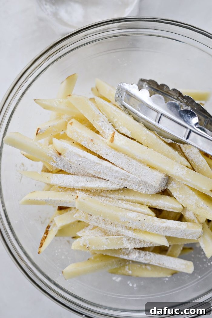 Golden Crispy Oven Fries 13 Close-up of potato fries thoroughly coated with seasoning and cornstarch, ready for baking.