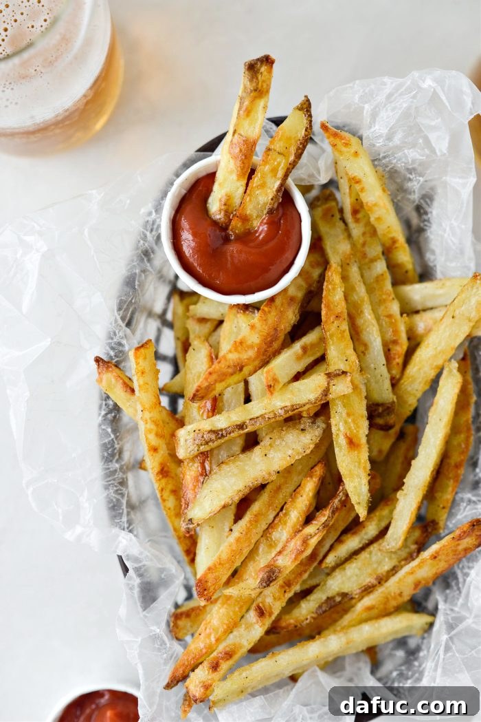 Golden Crispy Oven Fries 19 A large serving of oven baked French fries in a rustic metal basket, perfect for sharing.