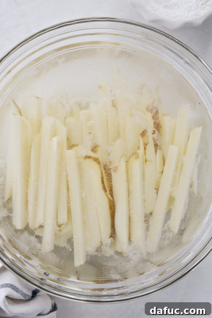 Golden Crispy Oven Fries 6 Cut potato sticks soaking in a bowl of cold water to remove excess starch.