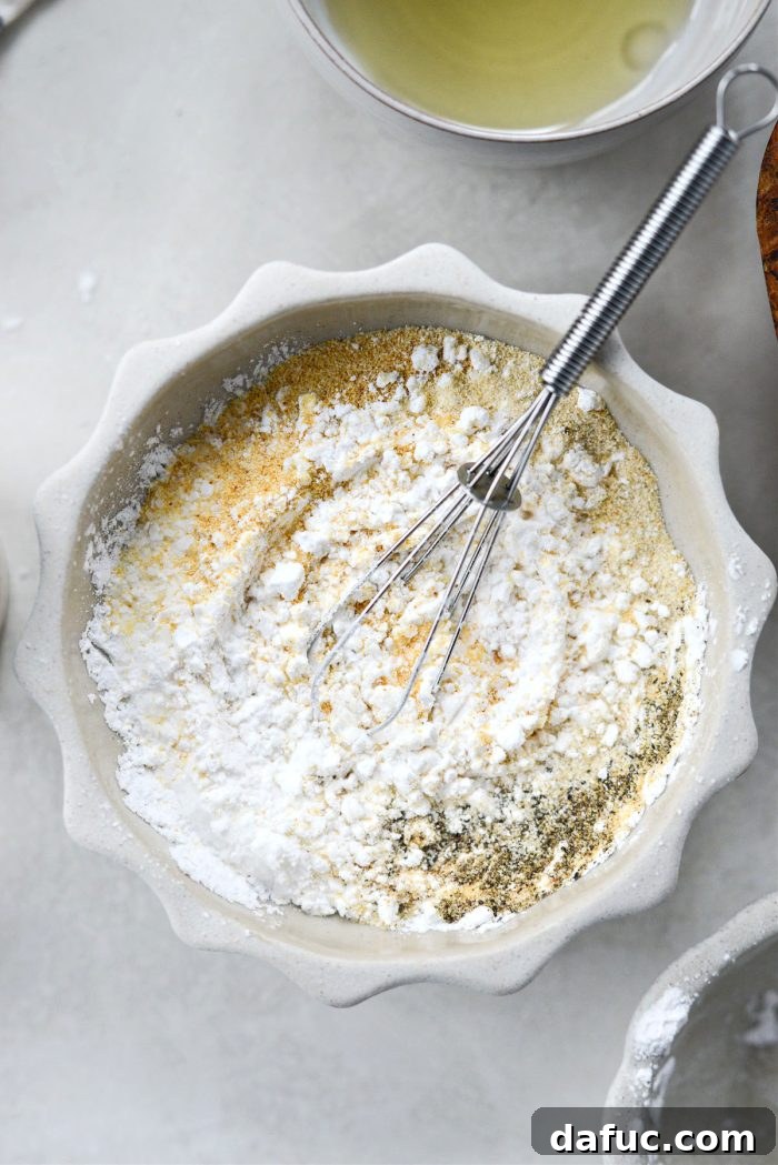 Golden Crispy Oven Fries 8 Hand whisking cornstarch and spices in a small bowl for the fry seasoning.