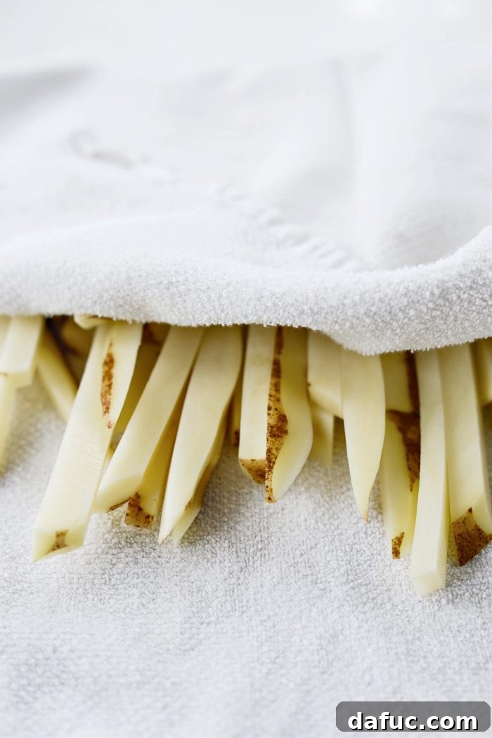 Golden Crispy Oven Fries 10 Clean kitchen towel with pat-dried potato fries, emphasizing the importance of dryness.