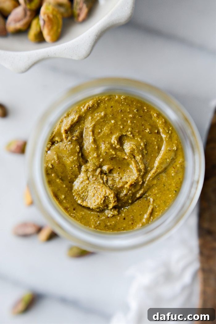 A bowl of creamy pistachio butter with a spoon, ready to be served or stored.