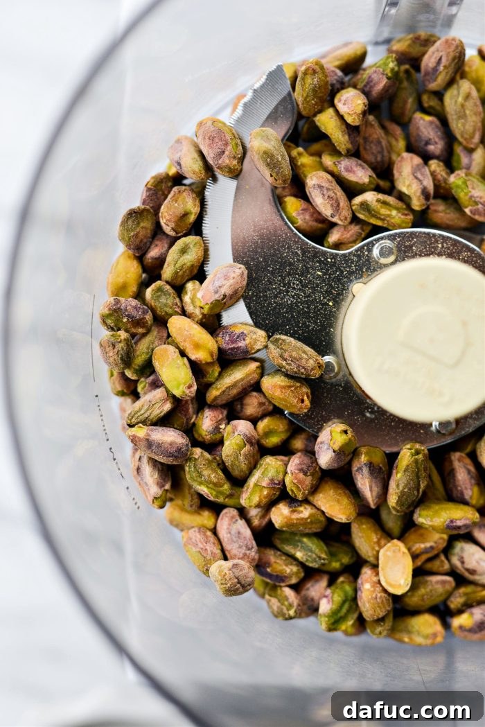 A food processor bowl filled with one cup of shelled pistachios.