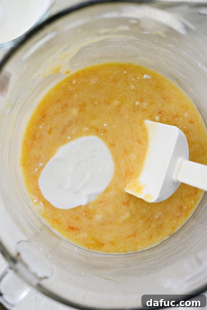 Creamy Grapefruit Zing Cake 12 The final addition of the sour cream mixture being stirred into the cake batter