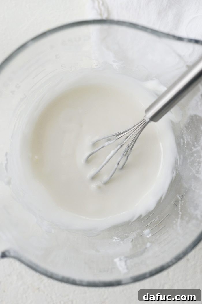 Creamy Grapefruit Zing Cake 15 Ingredients for the sour cream glaze, powdered sugar, sour cream, and milk, being whisked in a bowl