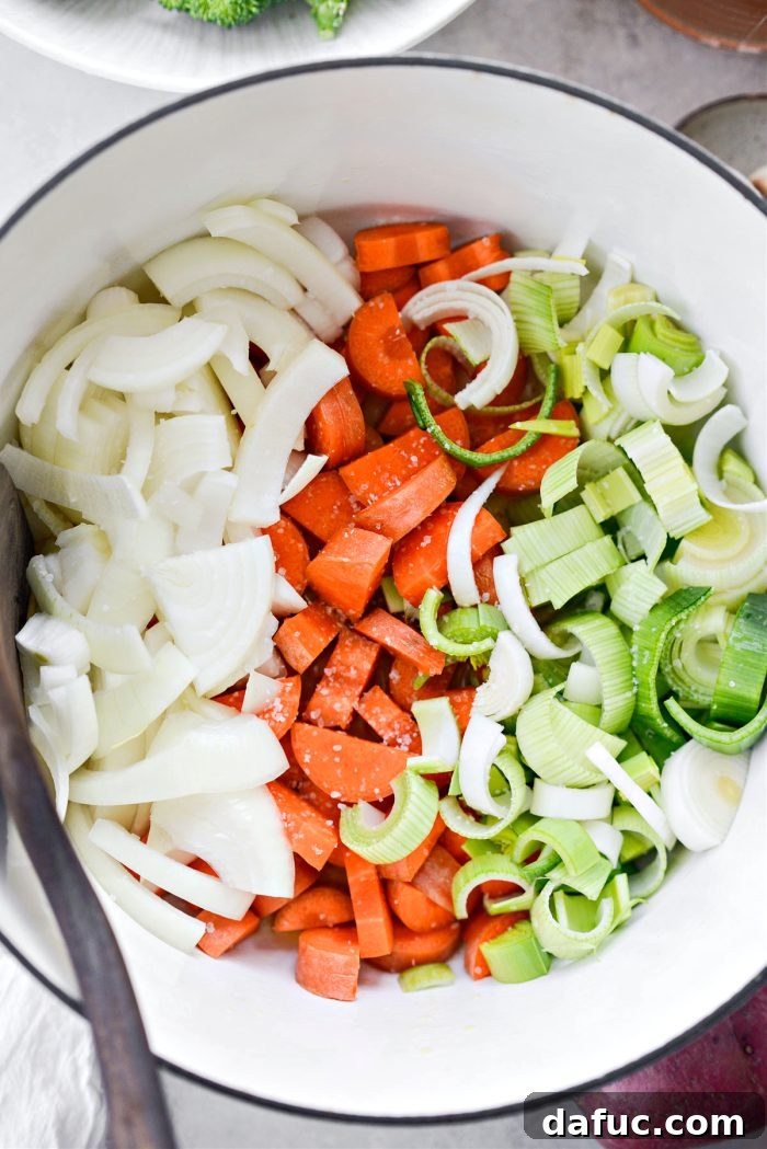 Hearty Irish Vegetable Soup 6 Roughly chopped carrots, onions, and sliced leeks being added to a pot with melted butter and oil.