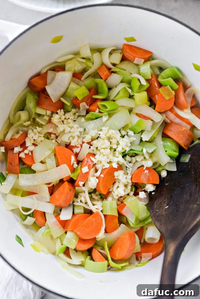 Hearty Irish Vegetable Soup 8 Minced garlic being added to sautéed vegetables in a pot.