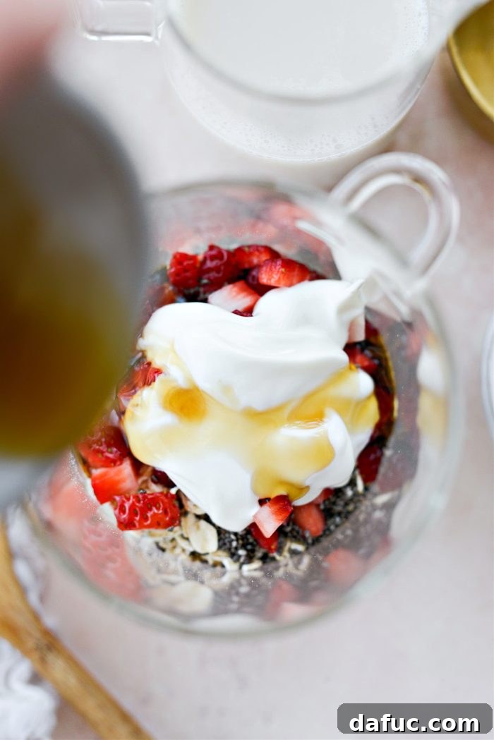 Creamy Strawberry Overnight Oats 6 Adding vanilla yogurt and maple syrup to the jar with oats, chia seeds, and strawberries.