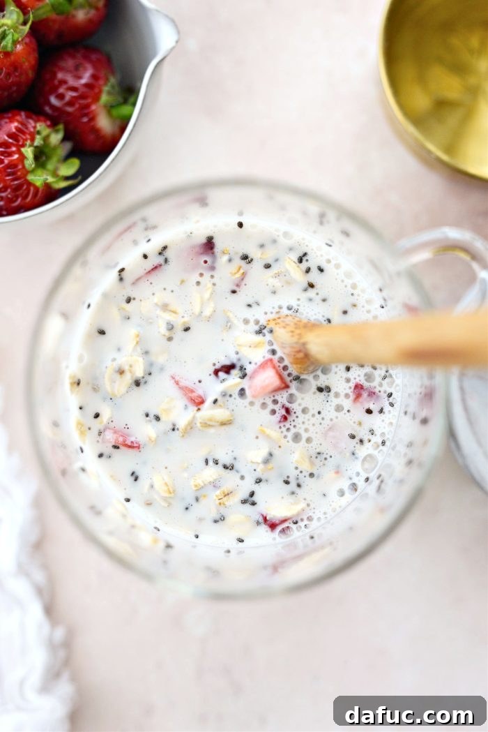 Creamy Strawberry Overnight Oats 8 The combined ingredients for overnight oats in a jar, ready to be stirred.