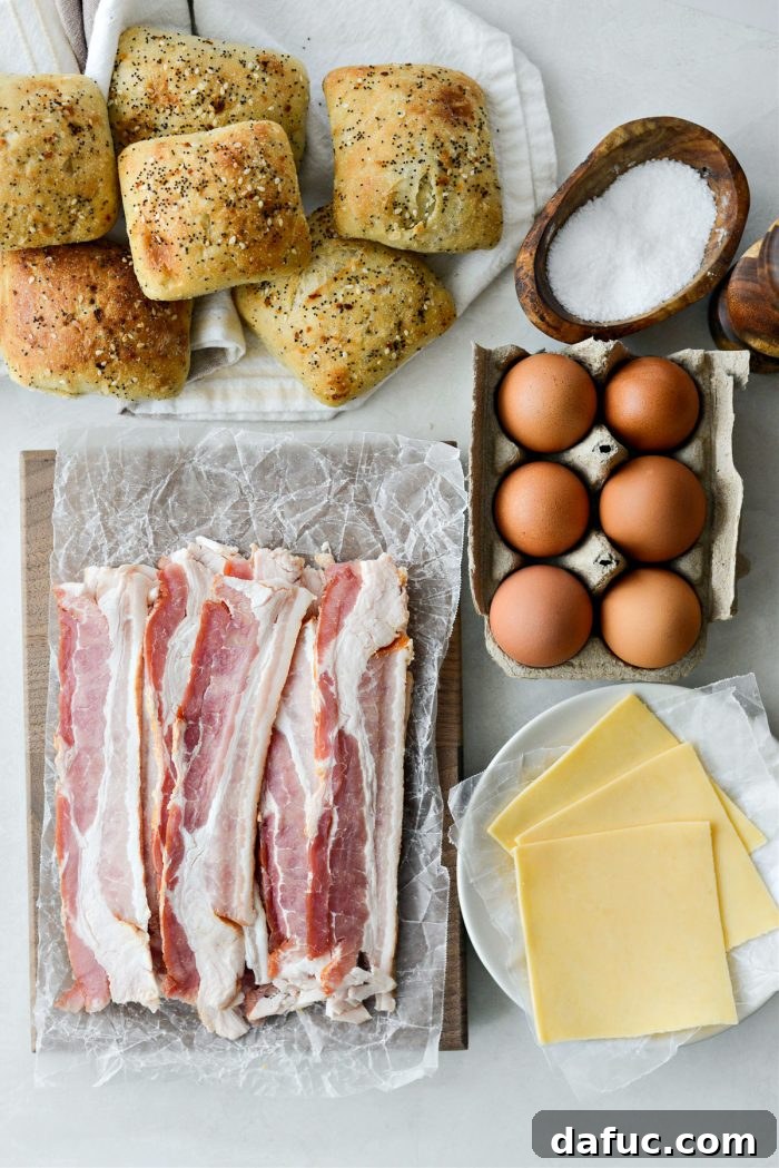 Ingredients laid out for Bacon Gouda Breakfast Sandwiches including rolls, bacon, eggs, and cheese