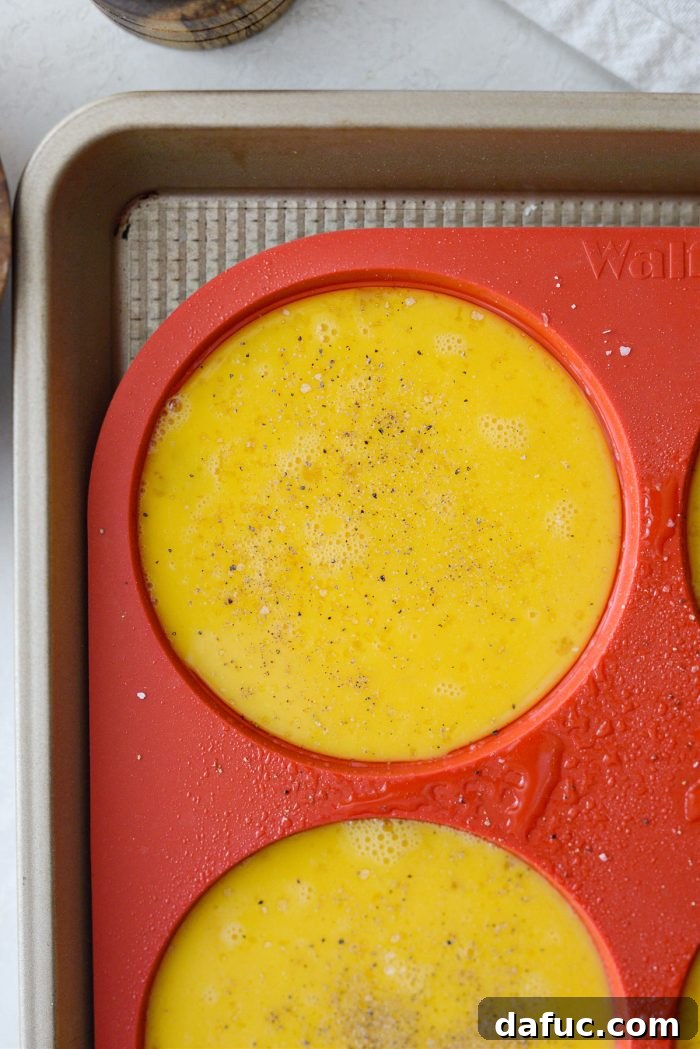 Whisked eggs being divided evenly among the silicone mold cavities