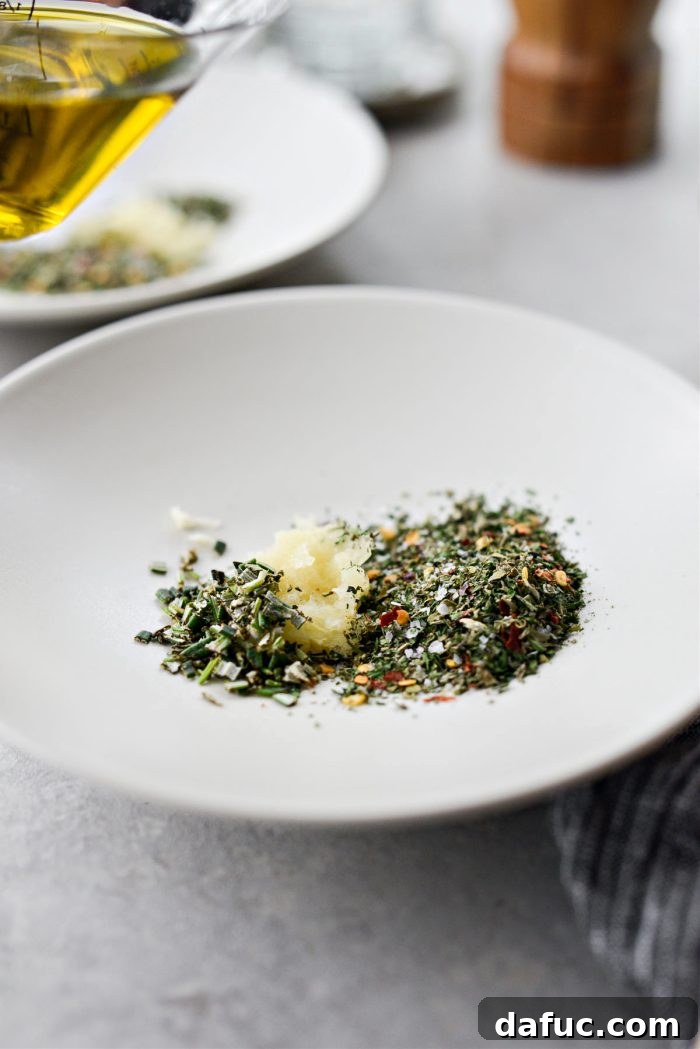 Garlic Herb Infused Dipping Oil 7 Dividing fresh garlic, rosemary, and dried herbs among two shallow plates