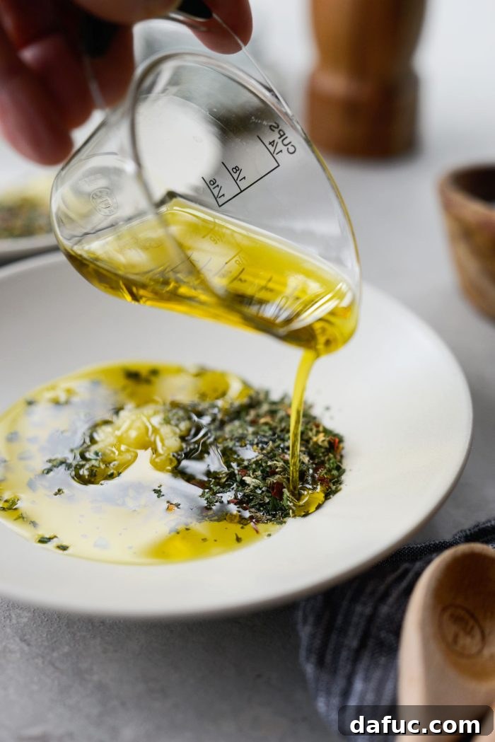 Garlic Herb Infused Dipping Oil 8 Pouring extra virgin olive oil onto herb and garlic mixture