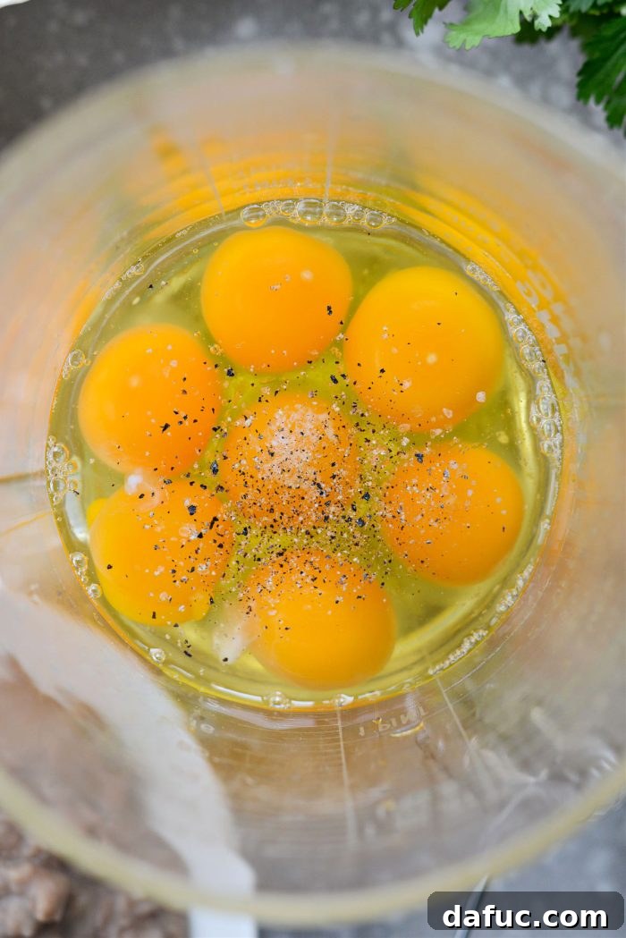 Cracking fresh eggs into a measuring cup for scrambling