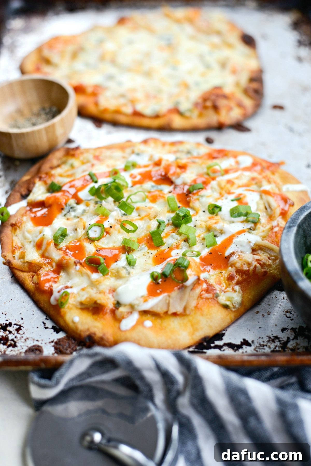 Buffalo Chicken Flatbread Pizzas garnished with sliced green onions and black pepper.