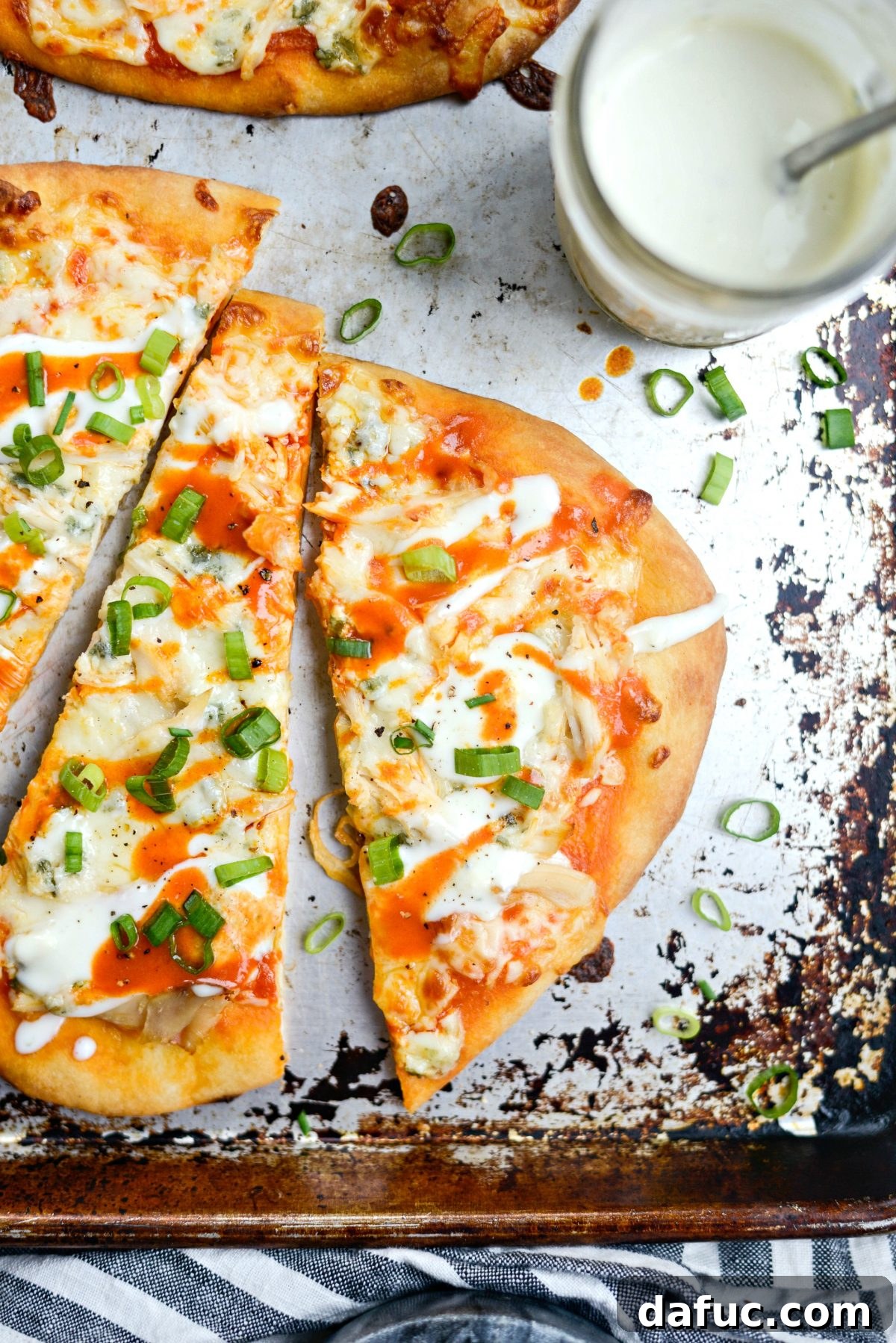 Two Buffalo Chicken Flatbread Pizzas on a cutting board, garnished and ready to be sliced.