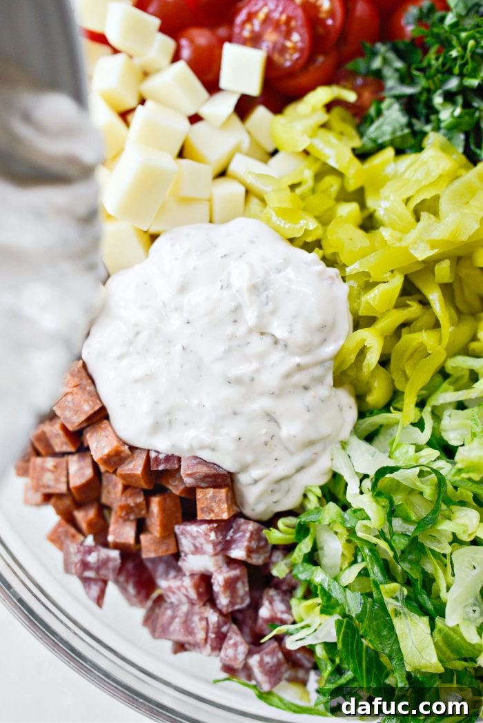 Pouring the creamy dressing over the pasta salad ingredients