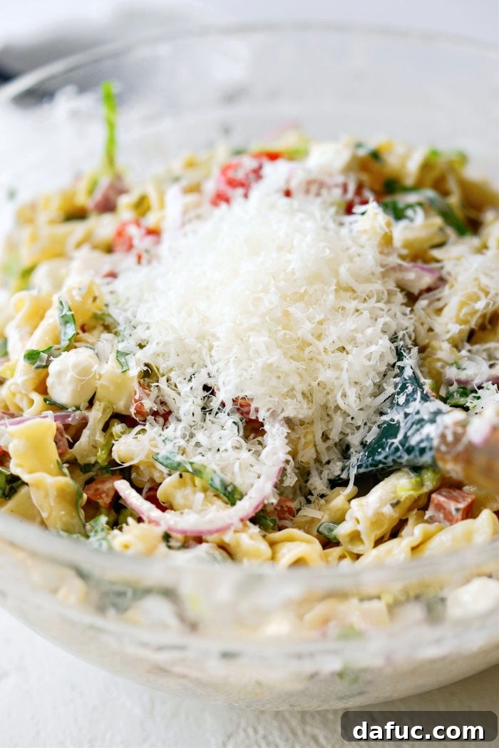 Adding freshly grated Parmesan cheese to the pasta salad