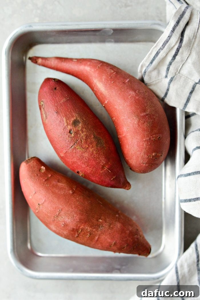 Velvety Sweet Potato Puree 4 Cleaned and patted dry sweet potatoes placed on a rimmed baking sheet, ready for the oven.