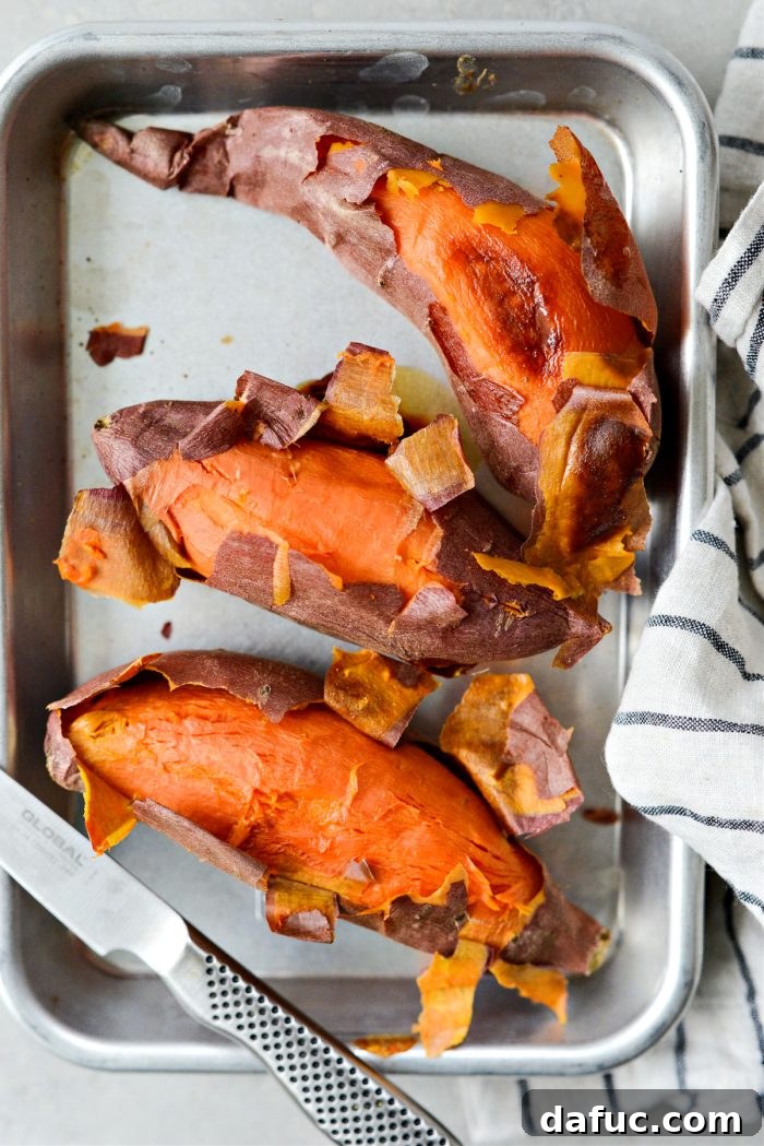 Velvety Sweet Potato Puree 6 A hand peeling a baked sweet potato, showing the soft, cooked flesh.
