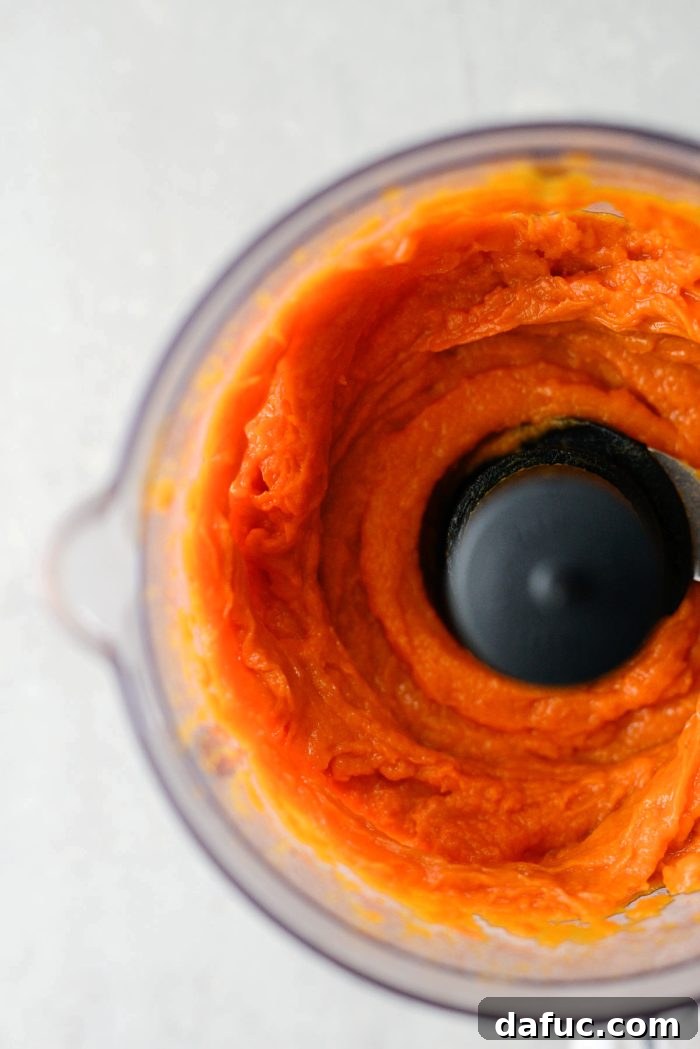 Velvety Sweet Potato Puree 8 Sweet potato pieces being blended in a food processor until smooth.
