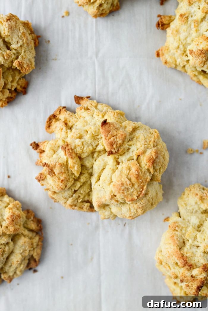 Effortlessly Fluffy Drop Biscuits 14 A close-up view of a split easy homemade drop biscuit, showing its flaky layers, served with a pat of butter.
