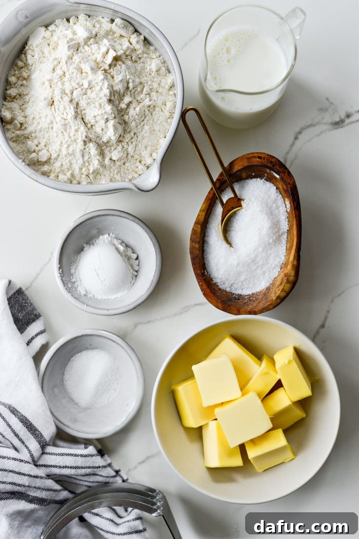 Effortlessly Fluffy Drop Biscuits 3 Easy Homemade Drop Biscuits Ingredients - A collection of flour, baking powder, sugar, salt, cold butter, and milk on a wooden board.