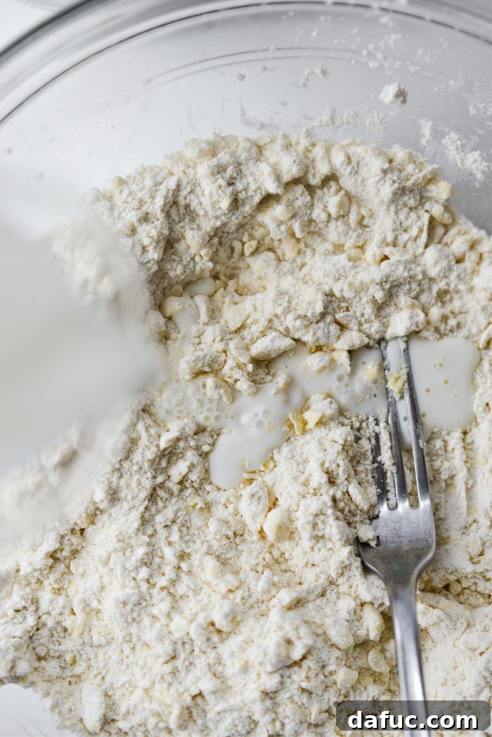 Effortlessly Fluffy Drop Biscuits 8 Pouring whole milk into the biscuit dough mixture.