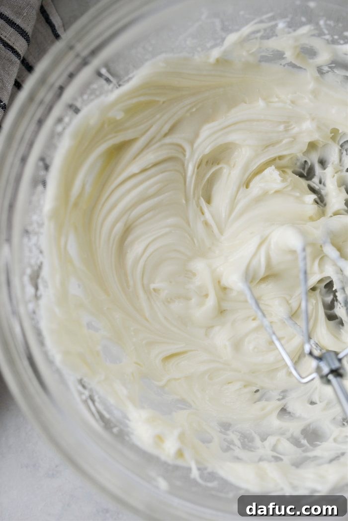 Lush Zucchini Cake with Cream Cheese Frosting 15 Mixing powdered sugar into the frosting until smooth and creamy