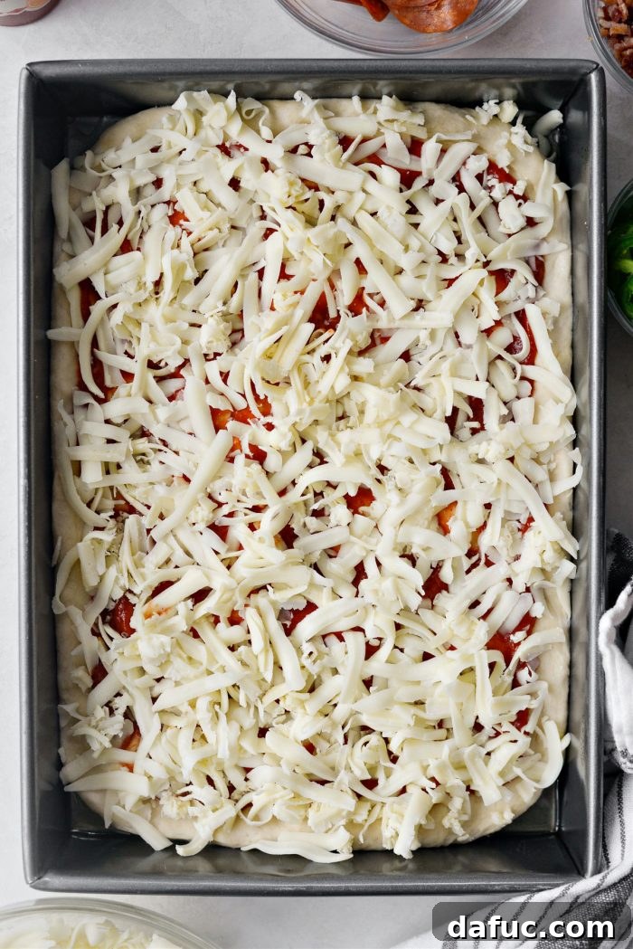 Half of the cheese mixture sprinkled on focaccia pizza dough