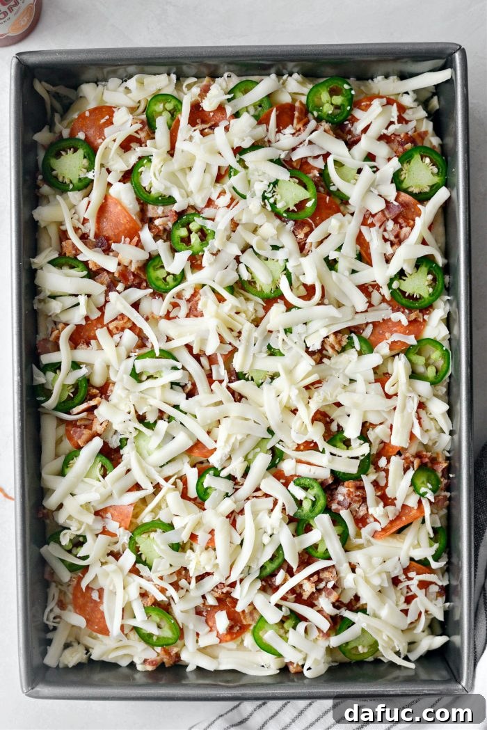 Remaining cheese sprinkled over the pizza, ready for baking