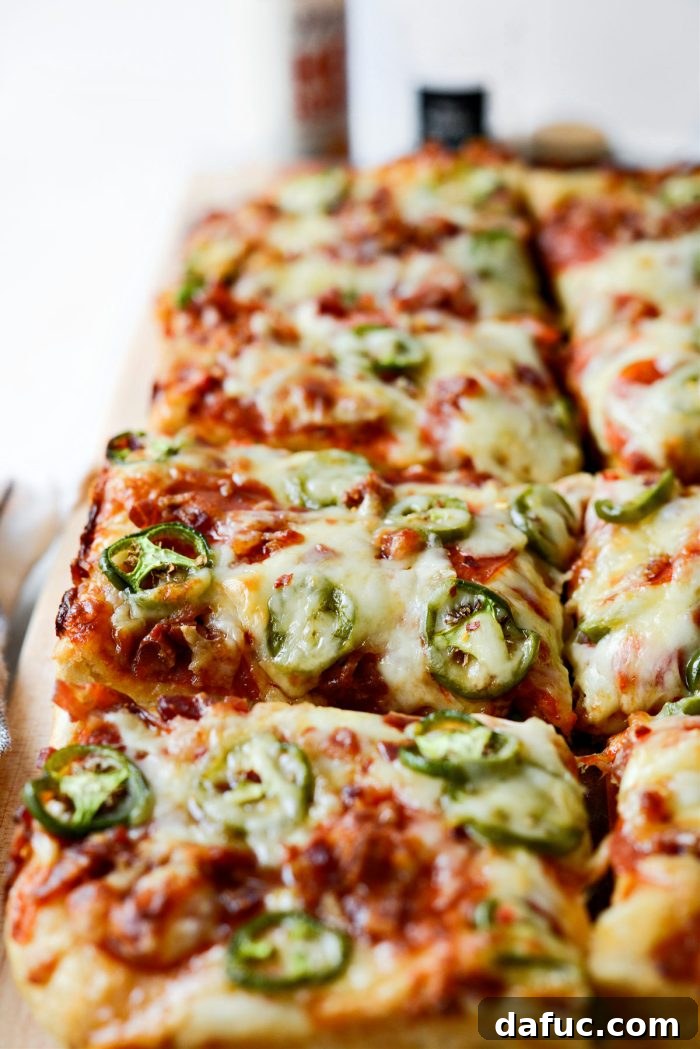 Close-up of a slice of Bacon Jalapeño Focaccia Pizza with melted cheese and toppings