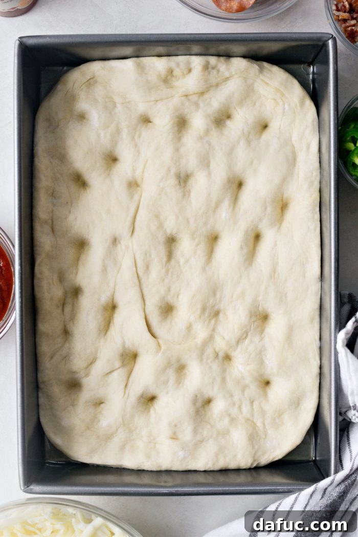 Making dimples in the focaccia dough with knuckles