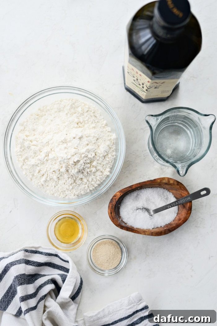 Fluffy Focaccia Pizza Dough Recipe 3 Various focaccia ingredients laid out on a kitchen counter: flour, salt, olive oil, yeast, honey, and water.
