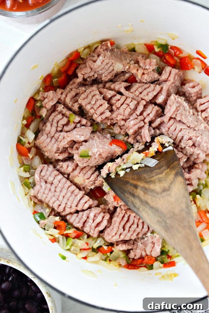 Adding spices to cooked turkey and vegetables for chili