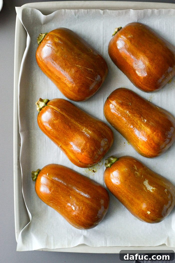Roasted honeynut squash halves on a baking sheet, partially cooked.