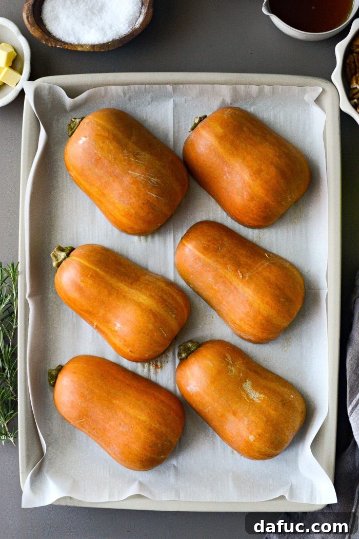 Honeynut squash halves placed cut-side down on a parchment-lined baking pan.