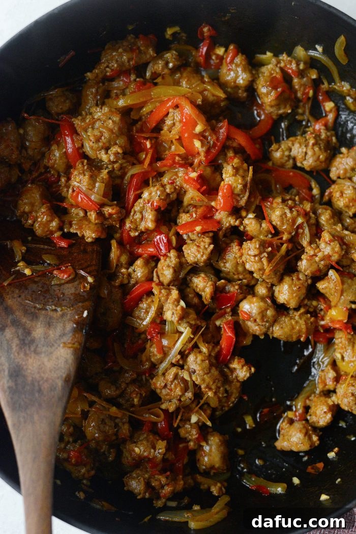 The cooked sausage and vegetable mixture with garlic and Calabrian chili paste, stirred and simmering in the skillet.