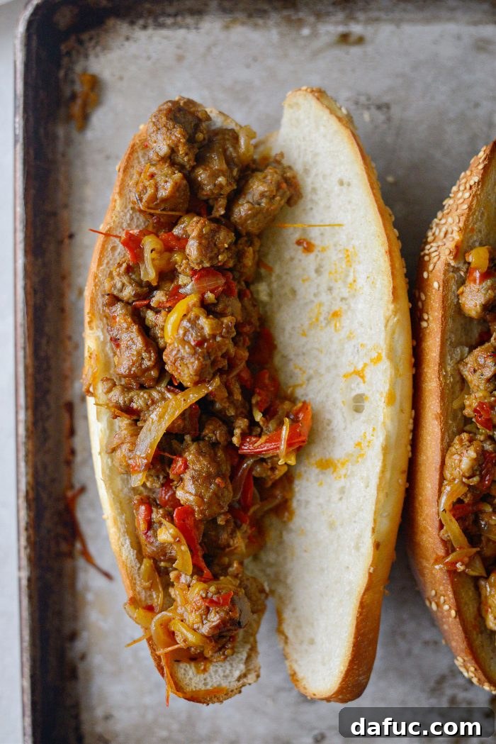 Toasted sub buns on a baking sheet, filled with the spicy Italian sausage and pepper mixture.