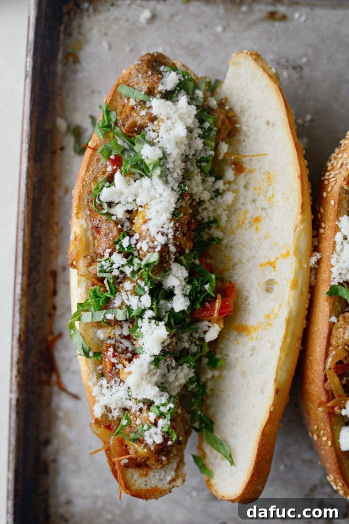 Fresh basil leaves and grated Pecorino Romano cheese sprinkled over the sausage and pepper filling in a sub bun.