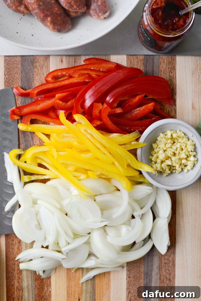 Hands thinly slicing red and yellow bell peppers and a yellow onion on a cutting board, with minced garlic cloves nearby, showing the prep work for the Spicy Italian Sausage Subs.
