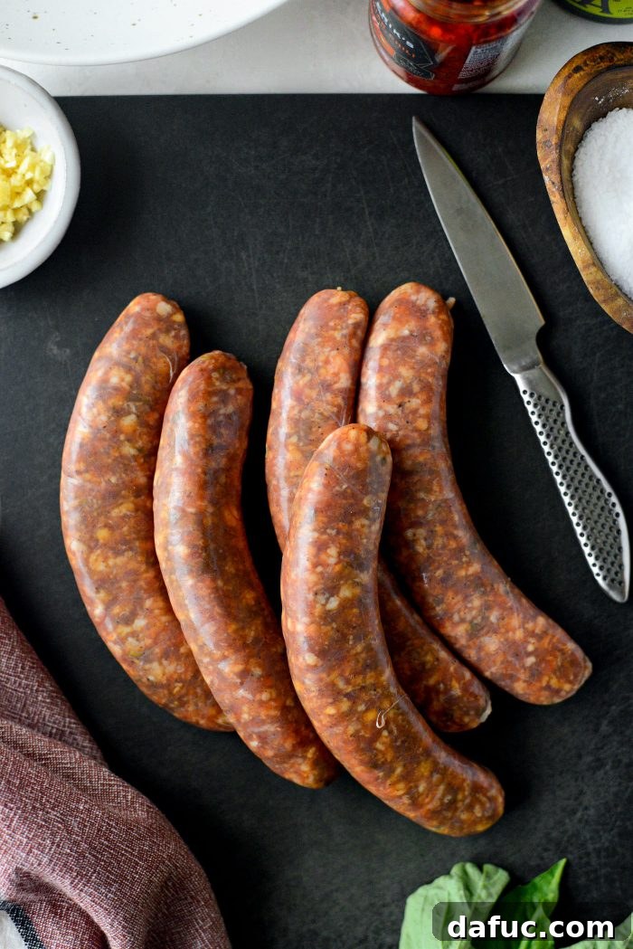 Hands removing the casing from spicy Italian sausage links on a cutting board, preparing them for chopping.