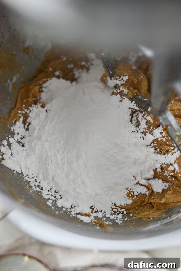 Gradually adding powdered sugar to frosting mixture