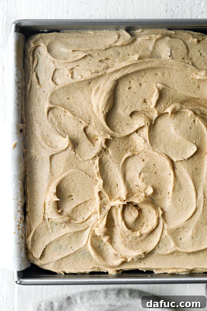 Spreading frosting evenly on top of the cake with an offset spatula