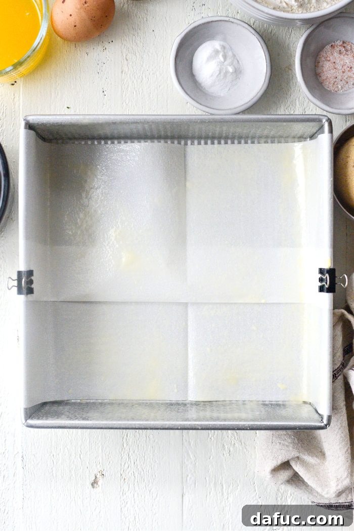 Preparing the baking pan by lining with parchment paper and spraying